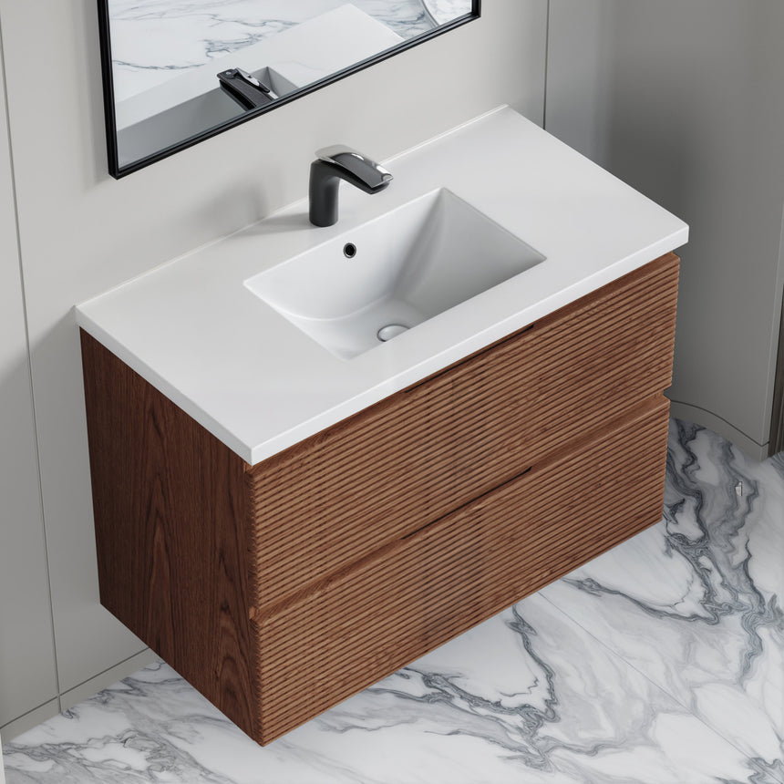 Bathroom vanity with wooden finish and white countertop against a gray wall.