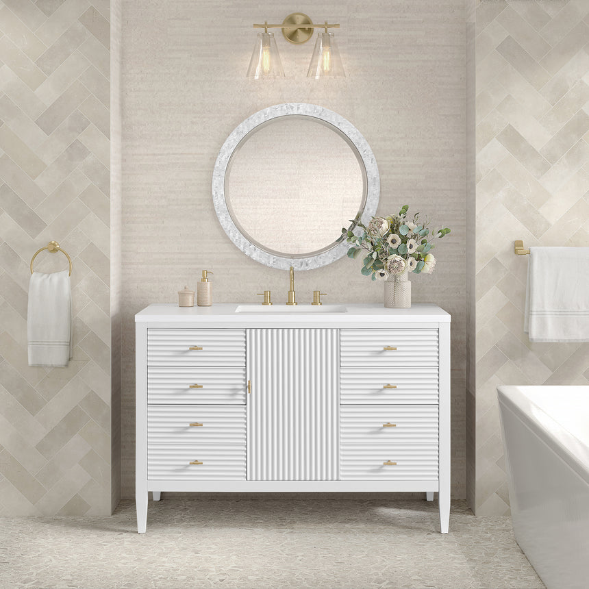 White bathroom vanity with marble countertop and decorative flowers in a bathroom setting.