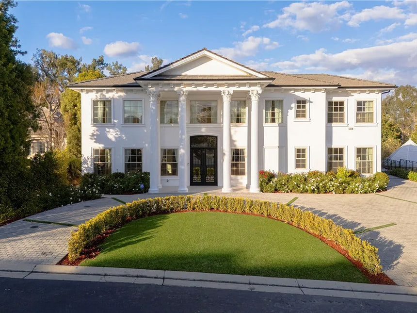 Front exterior of a luxury white Colonial-style estate with grand columns, circular driveway, and manicured lawn in Chino Hills, California.