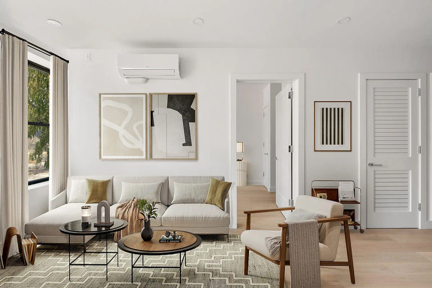 Mid-century modern living room with light sectional sofa, wood accent chair, geometric rug, abstract wall art, and neutral décor.