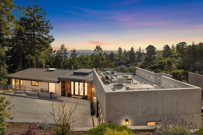Modern hillside home exterior at sunset with rooftop terrace