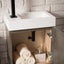 Bathroom vanity with white sink, black faucet, and towels inside a wooden cabinet.