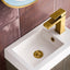 Bathroom sink with gold faucet against a tiled wall