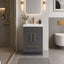 Modern bathroom with gray vanity, gold fixtures, and a mirror.