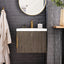 Bathroom with wooden vanity, round mirror, and plant against a gray brick wall.