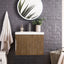 Bathroom with wooden vanity, round mirror, and dark brick wall.