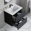 Bathroom vanity with open drawer displaying toiletries on a marble floor.