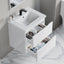Bathroom vanity with open drawer displaying various bottles on a marble floor.