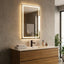 Bathroom vanity with illuminated mirror, sink, and decorative items.