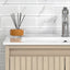 Bathroom vanity with a diffuser on the countertop and a tiled wall background