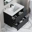 Bathroom vanity with open drawer displaying toiletries on a marble floor.