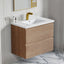Bathroom vanity with wooden cabinet, white countertop, and gold faucet.