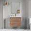 Bathroom vanity with wooden cabinet, mirror, and toiletries against a gray wall.