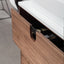 Wooden drawer with a black handle on a white countertop.