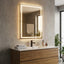 Bathroom vanity with illuminated mirror, sink, and decorative items.