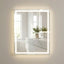 Bathroom with a large illuminated mirror reflecting a sink and plant.