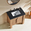 Bathroom vanity with black marble countertop and white sink against a beige wall.