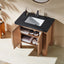 Bathroom vanity with black countertop and open cabinet showing toiletries.