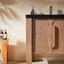 Wooden bathroom vanity with black countertop and decorative items against a beige wall.