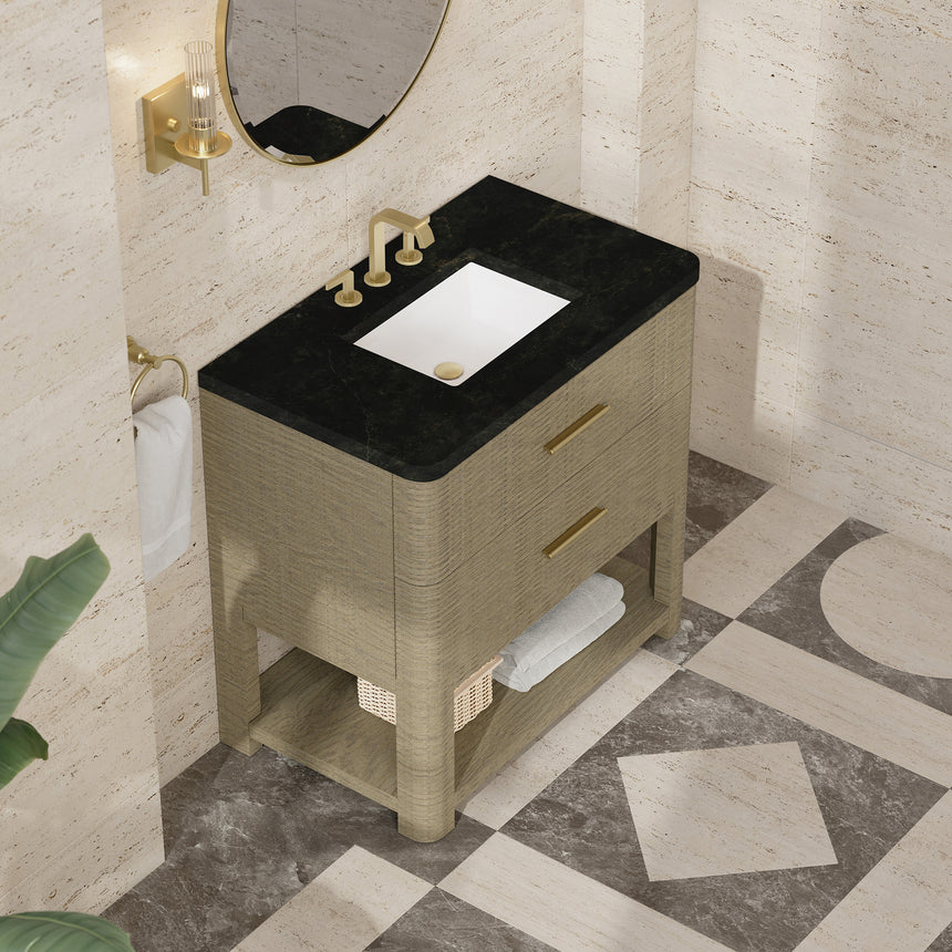 A modern bathroom vanity with a light oak wood frame, six drawers, an open lower shelf, and a white marble top with an integrated sink. The vanity is styled in a bright bathroom with a white freestanding tub, a gold faucet, and a glass shower stall in the background.