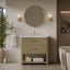 A modern bathroom vanity with a woven natural-fiber cabinet, white marble sink top, and a gold faucet, shown in a styled bathroom setting with a round mirror, wall sconces, towels, and a bathtub edge.