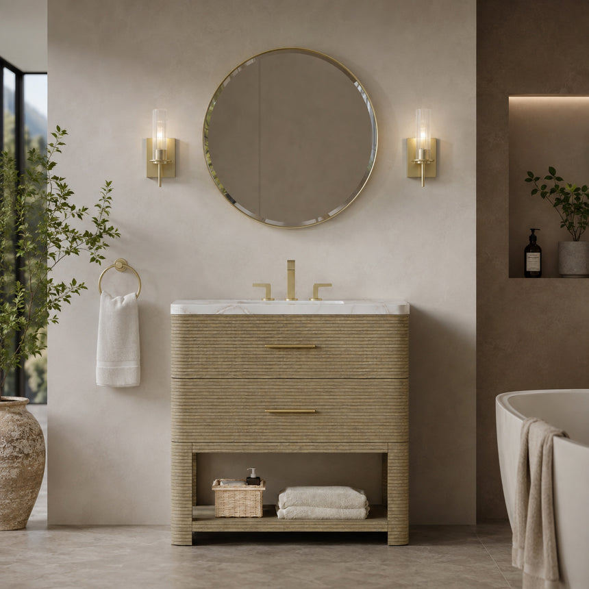 A modern bathroom vanity with a light oak wood frame, six drawers, an open lower shelf, and a white marble top with an integrated sink. The vanity is styled in a bright bathroom with a white freestanding tub, a gold faucet, and a glass shower stall in the background.