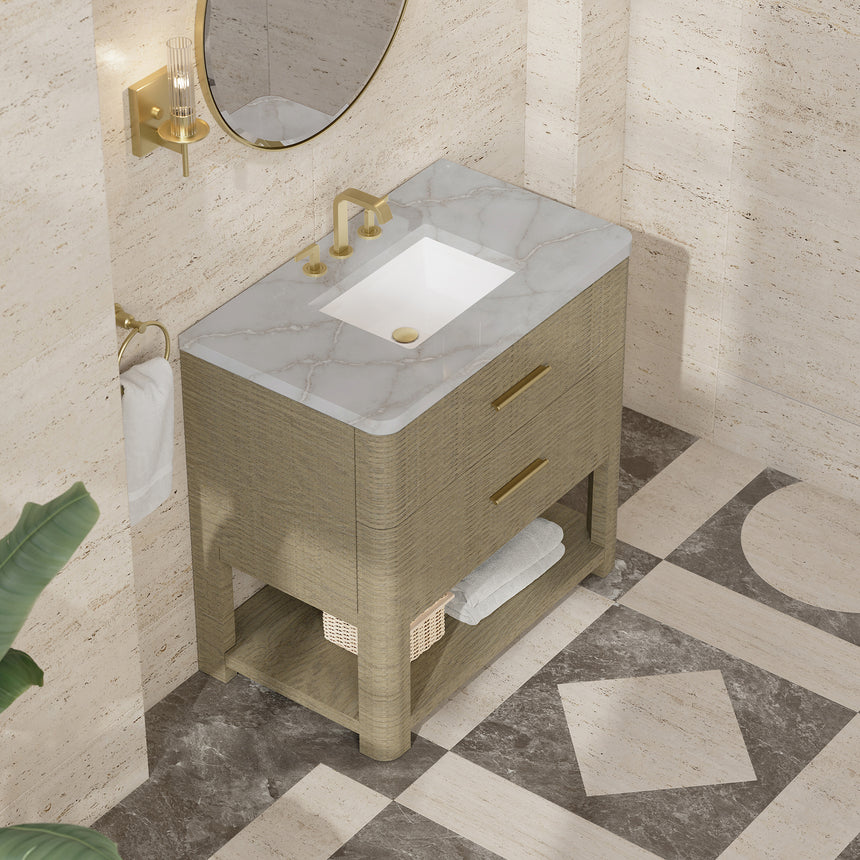 A modern bathroom vanity with a light oak wood frame, six drawers, an open lower shelf, and a white marble top with an integrated sink. The vanity is styled in a bright bathroom with a white freestanding tub, a gold faucet, and a glass shower stall in the background.