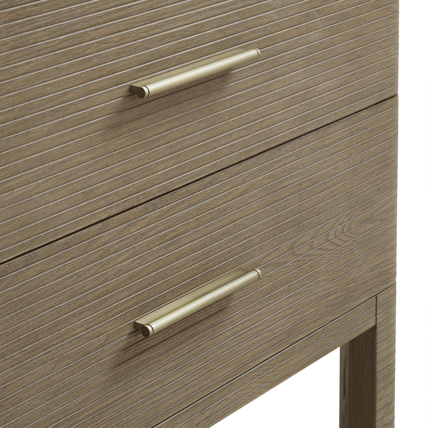 A modern bathroom vanity with a light oak wood frame, six drawers, an open lower shelf, and a white marble top with an integrated sink. The vanity is styled in a bright bathroom with a white freestanding tub, a gold faucet, and a glass shower stall in the background.