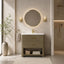 A modern bathroom vanity with a textured olive-green woven cabinet, white sink top, gold faucet and handles, and a matching round backlit mirror, shown in a styled bathroom setting.