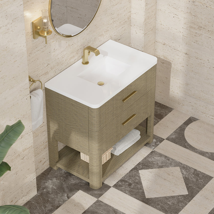 A modern bathroom vanity with a light oak wood frame, six drawers, an open lower shelf, and a white marble top with an integrated sink. The vanity is styled in a bright bathroom with a white freestanding tub, a gold faucet, and a glass shower stall in the background.