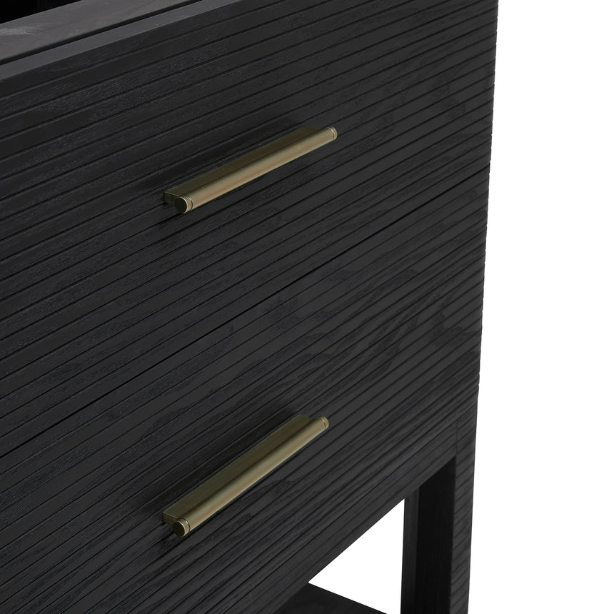 A modern bathroom vanity with a light oak wood frame, six drawers, an open lower shelf, and a white marble top with an integrated sink. The vanity is styled in a bright bathroom with a white freestanding tub, a gold faucet, and a glass shower stall in the background.