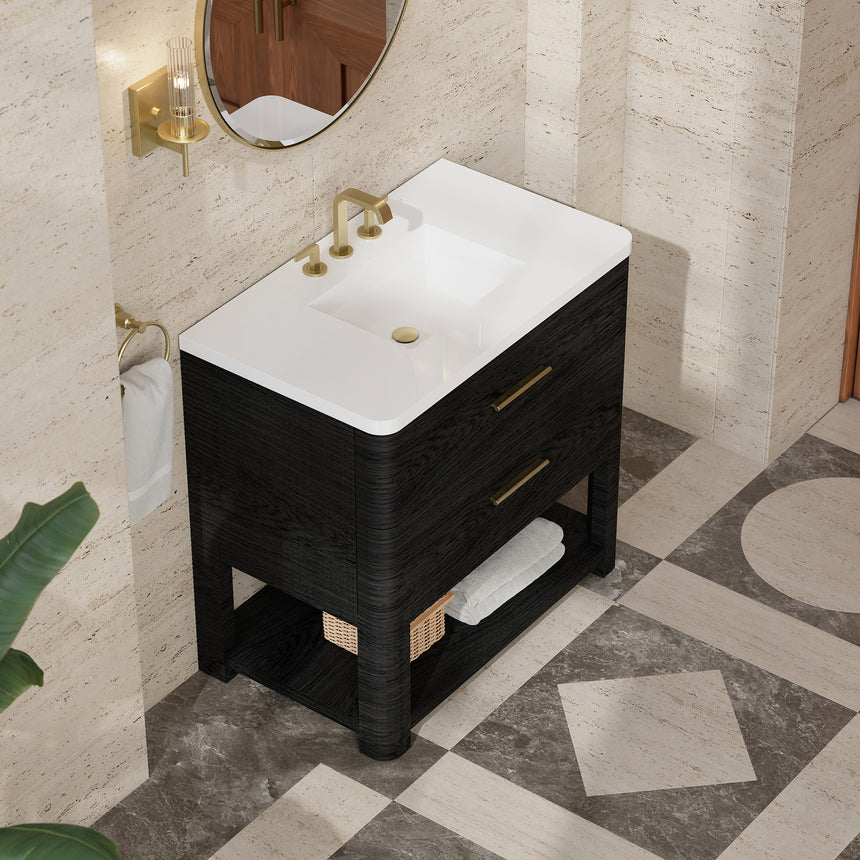 A modern bathroom vanity with a light oak wood frame, six drawers, an open lower shelf, and a white marble top with an integrated sink. The vanity is styled in a bright bathroom with a white freestanding tub, a gold faucet, and a glass shower stall in the background.