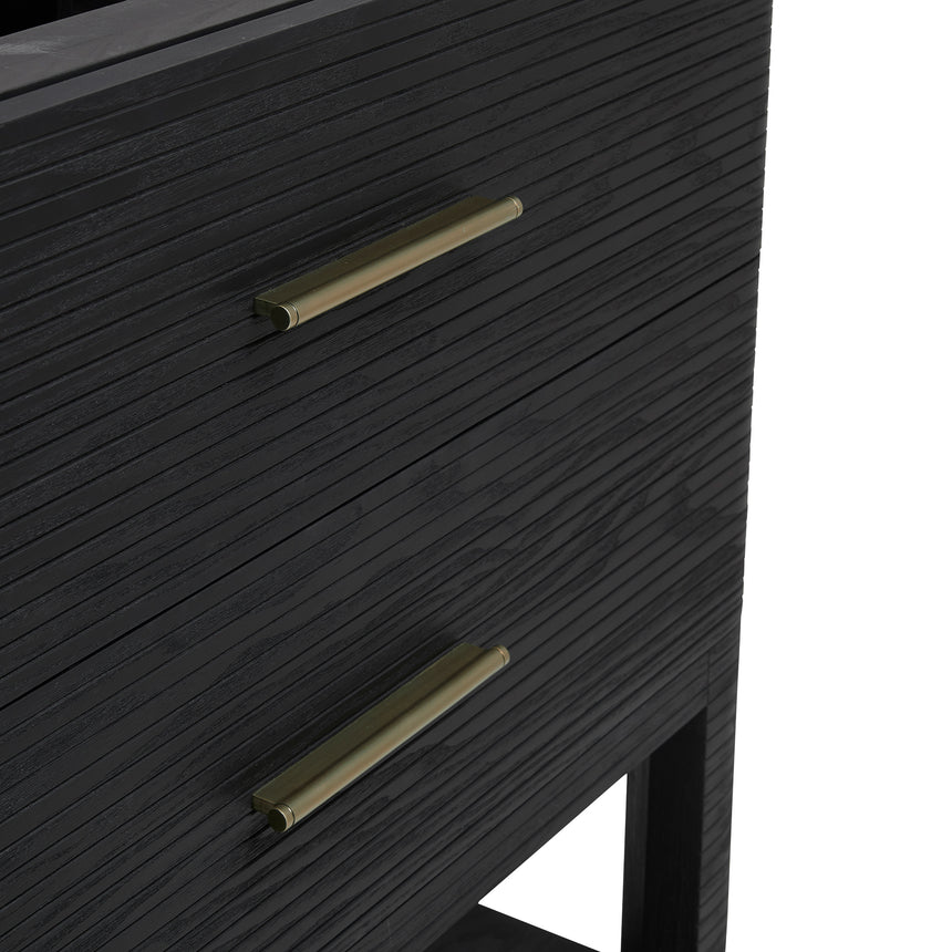 A modern bathroom vanity with a light oak wood frame, six drawers, an open lower shelf, and a white marble top with an integrated sink. The vanity is styled in a bright bathroom with a white freestanding tub, a gold faucet, and a glass shower stall in the background.