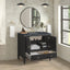 Bathroom vanity with open cabinet displaying towels and toiletries, round mirror above.