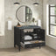 Bathroom vanity with open cabinet displaying towels and toiletries, round mirror above.