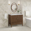 Bathroom vanity with wooden cabinet, mirror, and toiletries against a tiled wall.