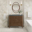 Bathroom vanity with wooden cabinet, round mirror, and decorative elements.