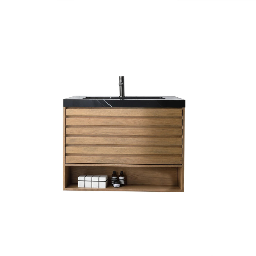 A modern floating bathroom vanity with a light oak wood finish, a white countertop, and an integrated sink, shown in a styled bathroom setting with a bathtub, shower glass, and decorative plants.