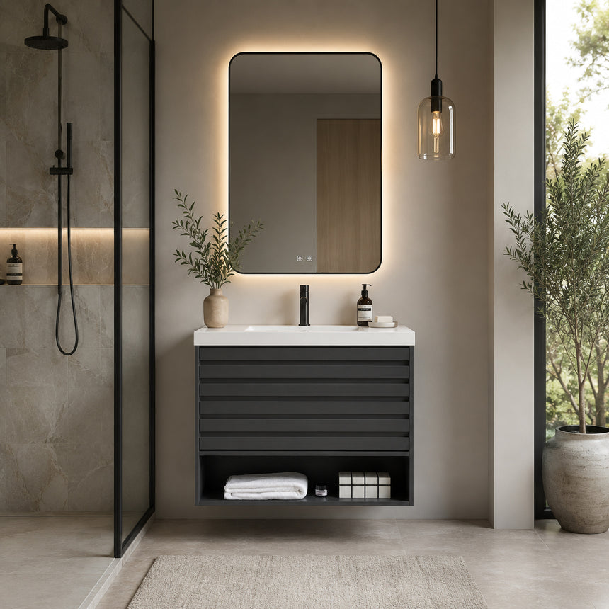 A modern floating bathroom vanity with a light oak wood finish, a white countertop, and an integrated sink, shown in a styled bathroom setting with a bathtub, shower glass, and decorative plants.