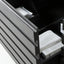 Close-up of a dark gray slatted drawer front with an open drawer containing white folded towels and a box, photographed in a clean interior setting.