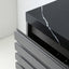 Close-up of a modern black cabinet or drawer unit with a glossy black marble-look top featuring a white veining pattern, and multiple dark gray slatted front drawers partially open.