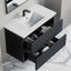 Bathroom vanity with open drawer displaying towels on a marble floor.