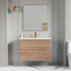 Bathroom vanity with wooden finish and mirror above it against a gray wall.