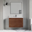 Bathroom vanity with wooden cabinet, mirror, and sink against a gray wall.