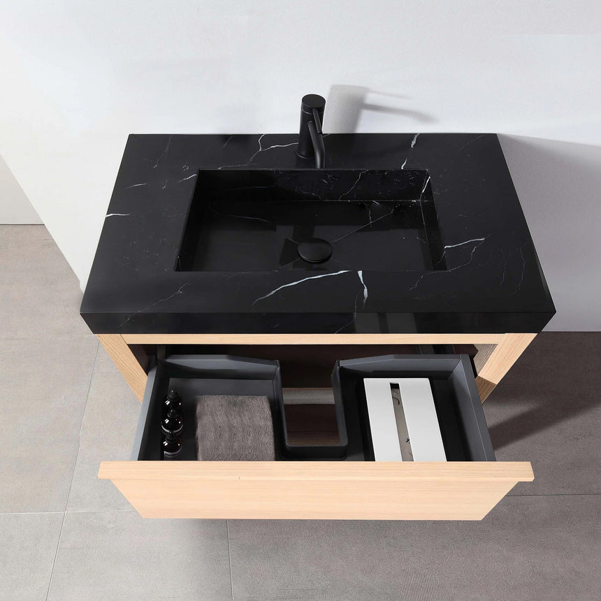 Bathroom vanity with black countertop and wooden cabinet in a bright room.