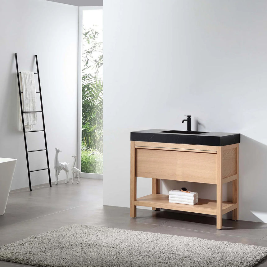 Bathroom vanity with black countertop and wooden cabinet in a bright room.
