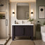 Modern bathroom with a dark vanity, mirror, and decorative elements.