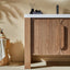 Wooden bathroom vanity with a white countertop against a beige wall.
