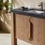 Bathroom vanity with wooden cabinets, black countertop, and sink.