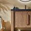 Bathroom vanity with wooden cabinet and black countertop, featuring a mirror and toiletries.